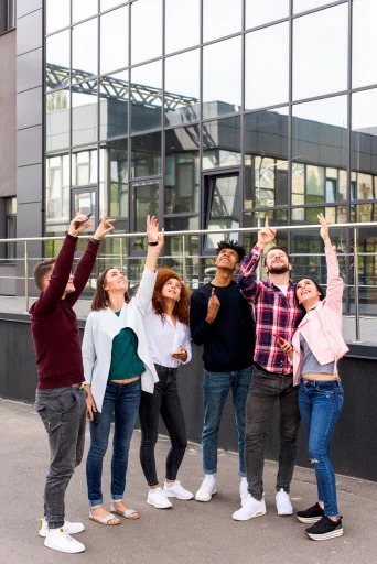 Students raising their hands together outside a building